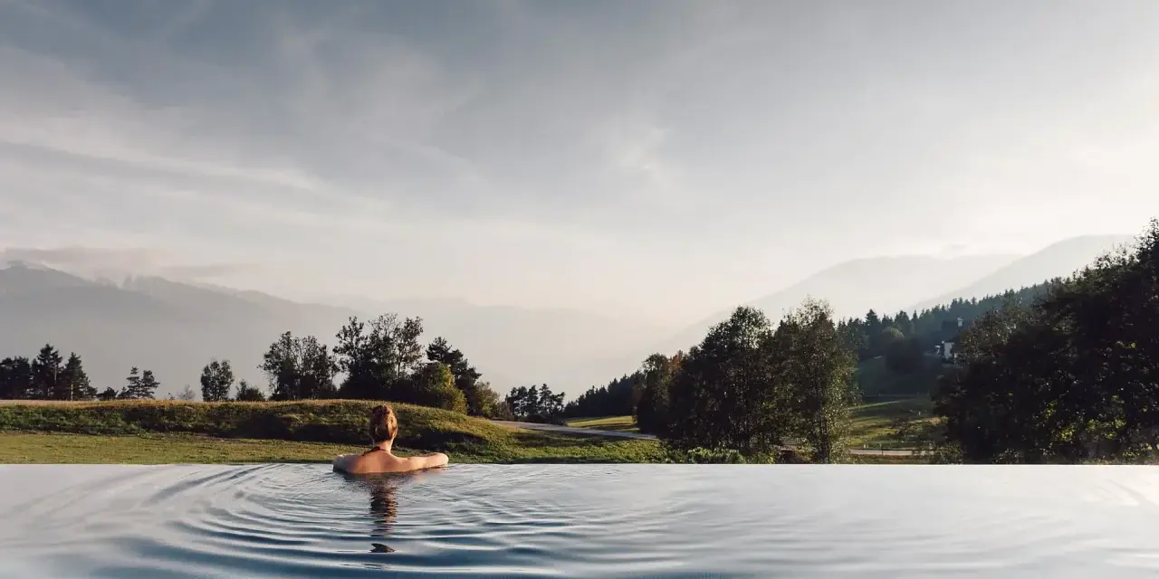 Donna rilassata in piscina a sfioro con vista sulle montagne, un'esperienza indimenticabile all'hotel Milla Montis.