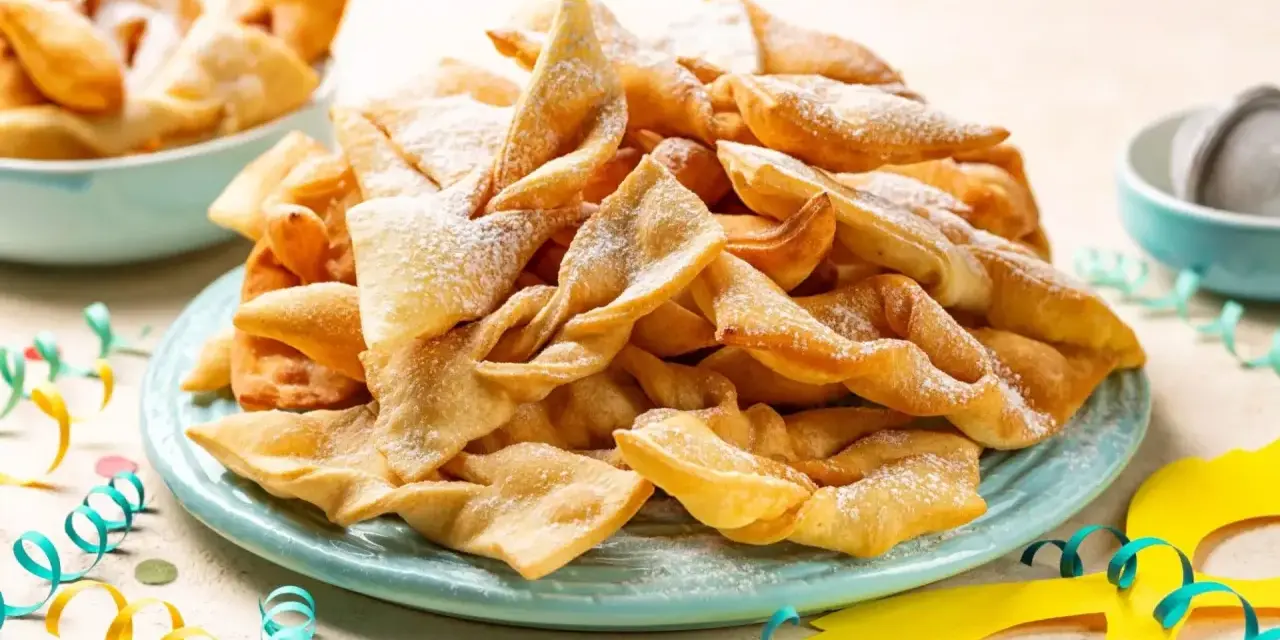 Dolci fritti a forma di fiocco, cosparsi di zucchero a velo, sono un classico di cosa si mangia a Carnevale in Italia.