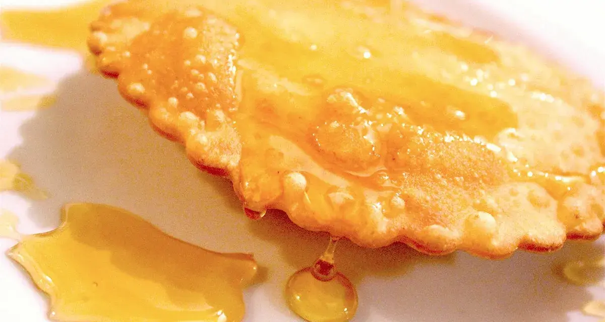 Dolce fritto, uno dei 5 piatti tipici della Sardegna, ricoperto di miele dorato.
