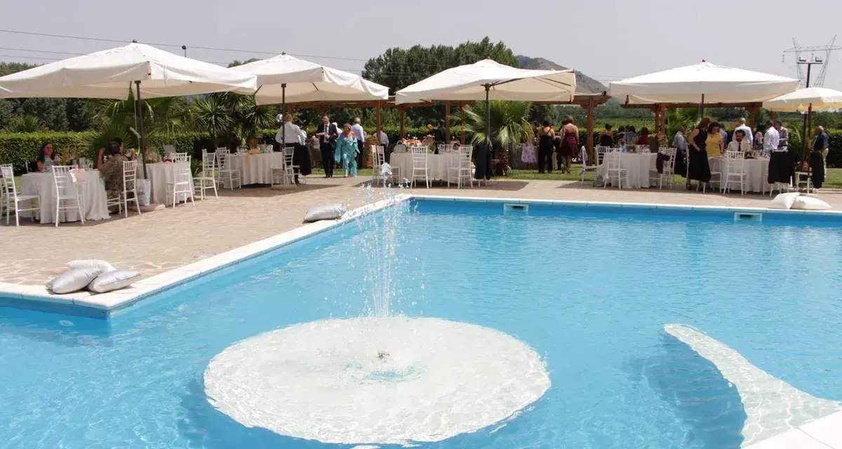 Un evento speciale alla Masseria Cardillo di Presenzano, con tavoli apparecchiati e ospiti vicino alla piscina con fontana.