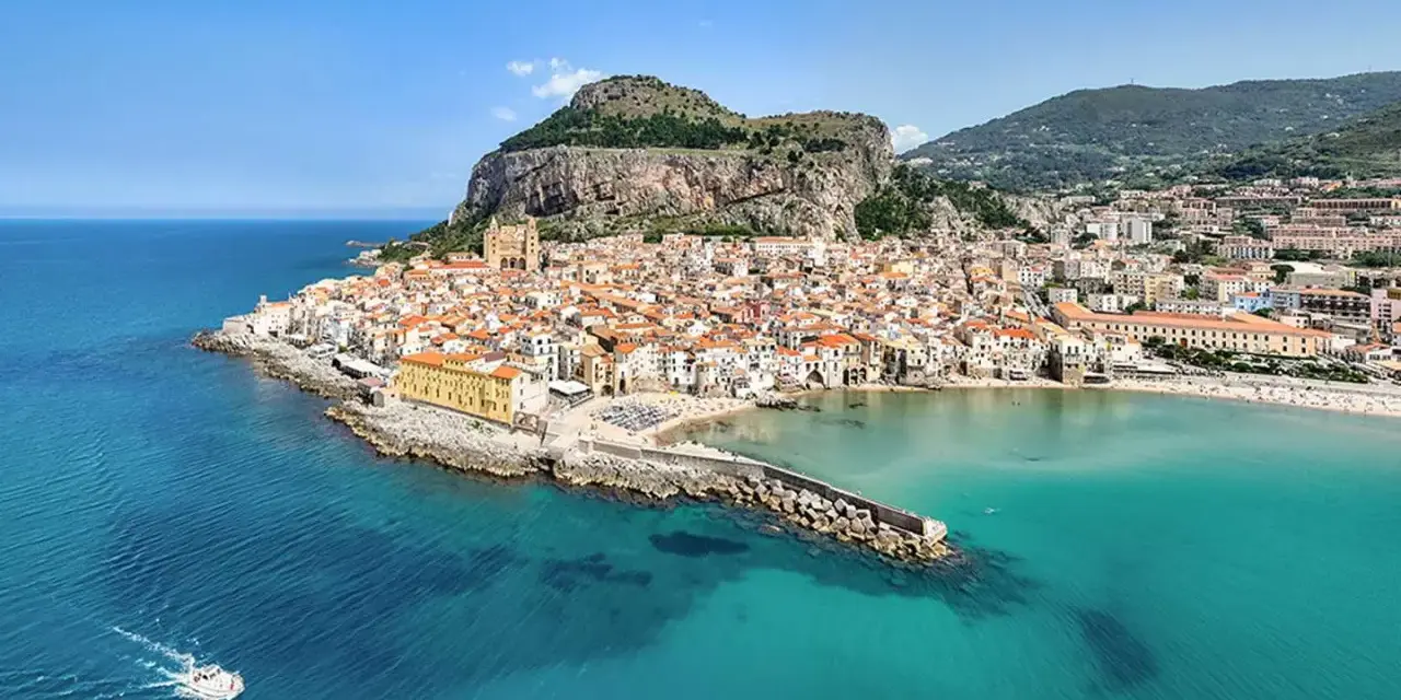 Vista aerea di Cefalù, con le sue spiagge siciliane orientali, il borgo arroccato e il mare cristallino.