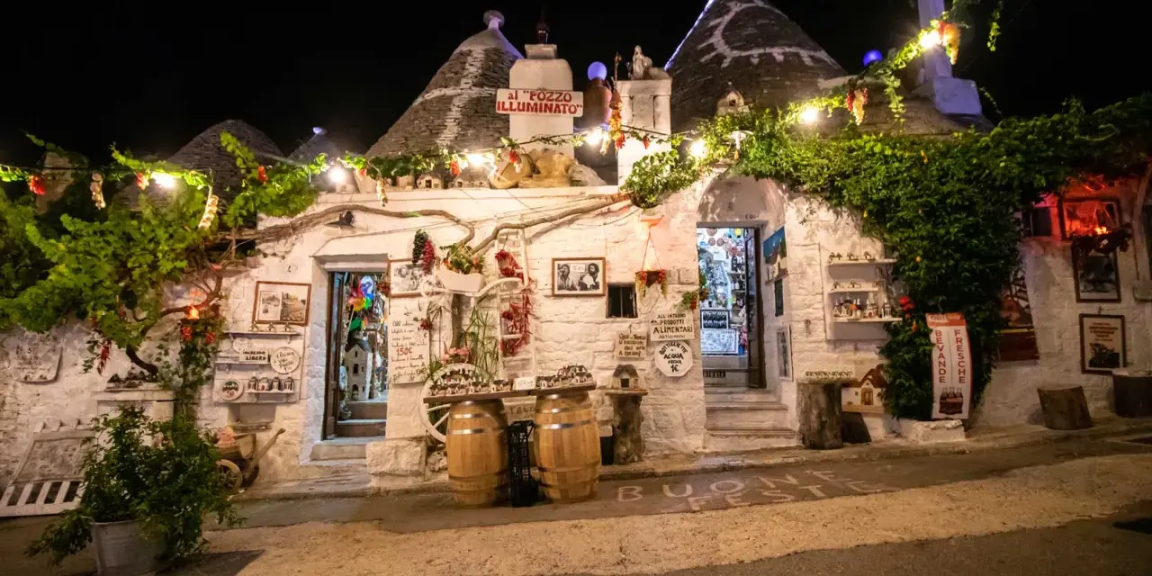 Trulli illuminati di notte ad Alberobello, con luci e decorazioni. Un invito a scoprire le cose da fare a Alberobello, tra negozi e prodotti tipici.