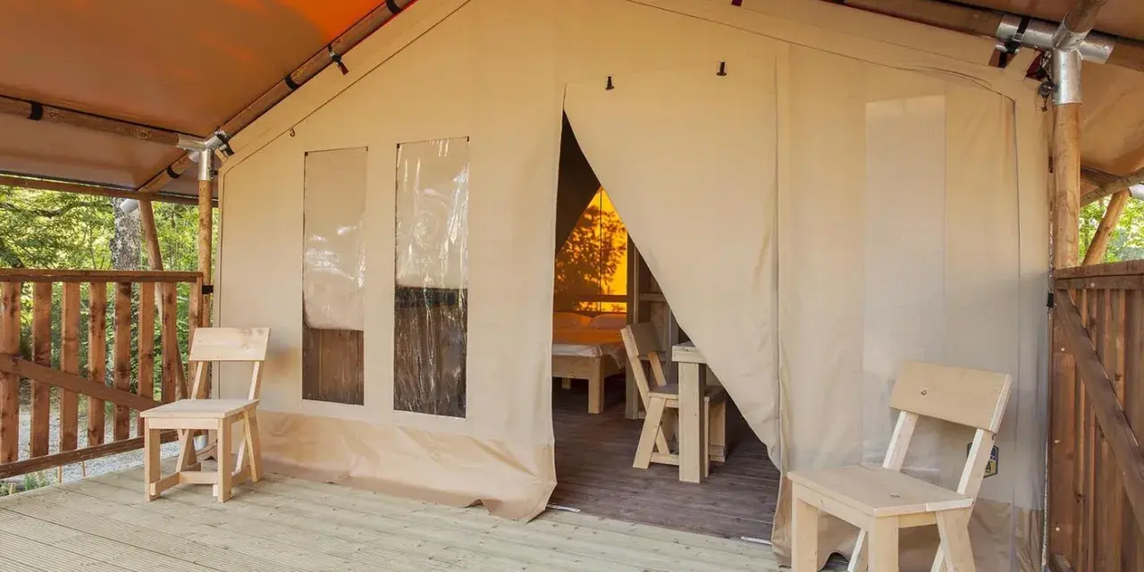Tenda accogliente nel Luxor Chianti Glamping Village, con sedie in legno sulla veranda e vista sull'interno arredato.
