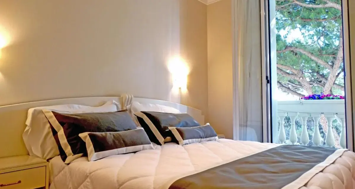 Camera accogliente con letto comodo e balcone fiorito. Ideale per chi cerca hotel Novecento Riccione recensioni positive.