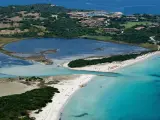 Vista aerea della spiaggia La Cinta con acque turchesi, lagune interne e vegetazione lussureggiante.