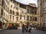 Un gruppo di turisti con valigie a rotelle cammina in una piazza fiorentina, un'immagine perfetta per un **viaggio in Toscana**.
