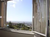 La terrazza sulla valle offre una vista panoramica su un paesaggio collinare con case e alberi verdi sotto un cielo azzurro.