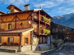 Casa in legno con balconi fioriti e montagne sullo sfondo. Un cartello "Alle Meridiane" indica un luogo incantevole a Lagopesole.