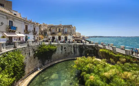 Passeggiata sul lungomare di Ortigia, Siracusa, ideale per un tour sicilia sud orientale 7 giorni. L'acqua cristallina e i papiri incantano.