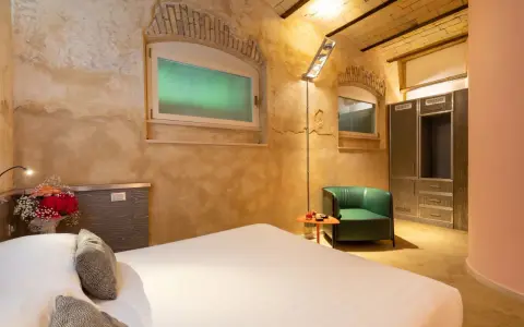 Camera accogliente con letto, poltrona verde e armadio. Un tocco di lusso, come un boscolo circo massimo, per un soggiorno indimenticabile.