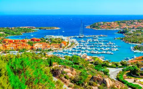 Vista panoramica di Porto Cervo con il suo porto turistico pieno di yacht e le case colorate che si affacciano sul mare cristallino. Un luogo da sogno per scoprire cosa vedere a Porto Cervo.