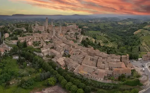 Panoramica aerea di San Gimignano, con le sue torri medievali che svettano tra i tetti rossi. Un sogno di **Volterra e San Gimignano in un giorno**.