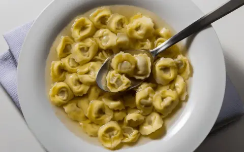 Tortellini in brodo, uno dei piatti tipici di Ravenna, serviti in una ciotola bianca con un cucchiaio.