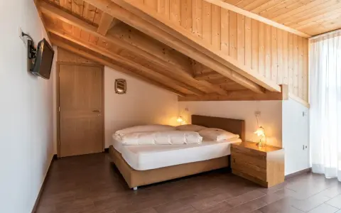 Camera accogliente con tetto in legno e letto matrimoniale. Un'oasi di pace all'hotel Weingarten Kaltern.