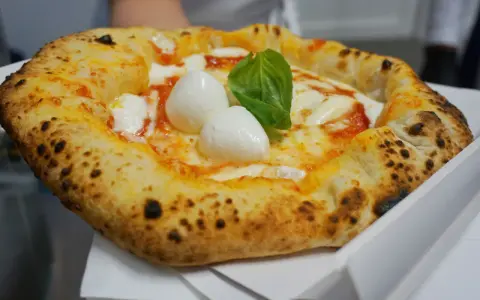 Pizza Margherita appena sfornata, con mozzarella di bufala e basilico fresco. Un vero assaggio di cibo napoletano.