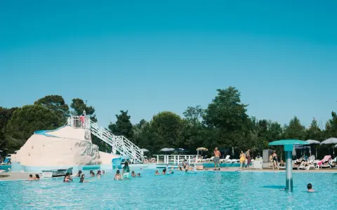 Bambini e adulti si divertono nella piscina del villaggio Ca' Laguna, con scivoli e zone relax sotto il sole.
