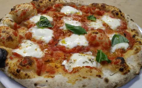 Pizza margherita con mozzarella filante, pomodoro e basilico fresco. Una vera casa matta, nota per la sua bontà.
