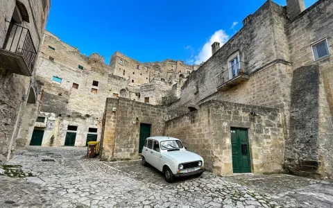 Un'auto d'epoca bianca in un vicolo di Matera, perfetta per visitare la città in un giorno.