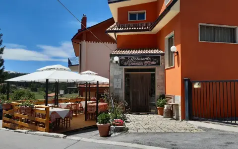Ristorante La Vecchia Fonte, con tavoli all'aperto sotto ombrelloni bianchi, in una giornata di sole.