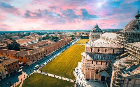 Un suggestivo itinerario Toscana 5 giorni inizia con la Piazza dei Miracoli a Pisa, con la sua cattedrale e il battistero sotto un cielo rosa.