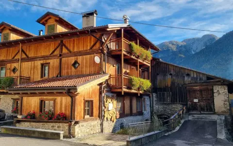 Casa in legno con balconi fioriti e montagne sullo sfondo. Un cartello "Alle Meridiane" indica un luogo incantevole a Lagopesole.