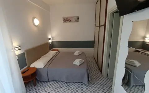 Camera accogliente con letto matrimoniale, biancheria fresca e un tavolino. Le recensioni per Hotel Le Terrazze Riccione confermano la comodità.