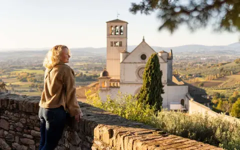 Donna ammira il panorama di Assisi, con la Basilica di San Francesco in lontananza. Un ricordo di viaggio tra Assisi e Gubbio.