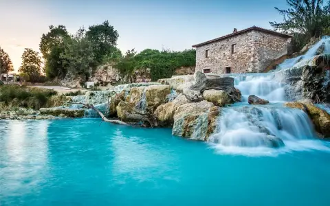 Cascate naturali con acqua turchese e un antico mulino in pietra. Un'oasi di pace, perfetta per un inverno nelle terme in Italia.