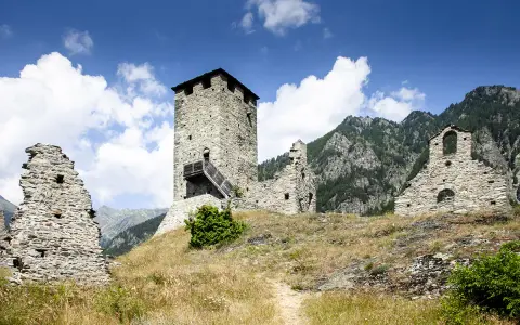 Rovine di un castello con torre in pietra, un invito a visitare la Valle d'Aosta.