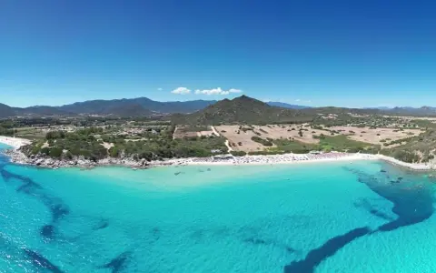Spiaggia di Castiadas con acque cristalline e montagne sullo sfondo. Un luogo da sogno, quasi come vedere il delfino Castiadas nuotare felice.