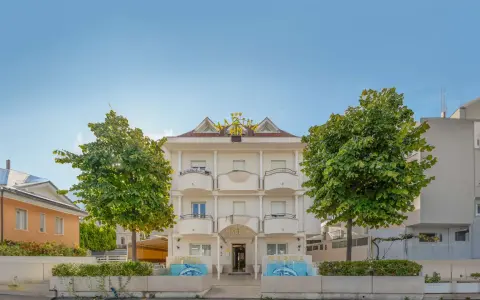 Hotel Marina Riccione: facciata bianca con insegna dorata, alberi verdi e fontane. Le recensioni lo descrivono come un'ottima scelta.