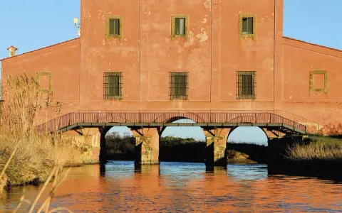 Antico edificio con ponte ad archi su un canale, un luogo suggestivo da scoprire a Castiglione della Pescaia.