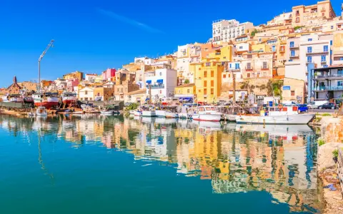 Porto di Sciacca: case colorate a picco sul mare, barche da pesca ormeggiate e riflessi sull'acqua. Un luogo incantevole da scoprire.