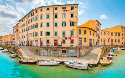 Canali di Livorno, cosa vedere in un giorno: case colorate affacciate sull'acqua, barche ormeggiate e panni stesi al sole.