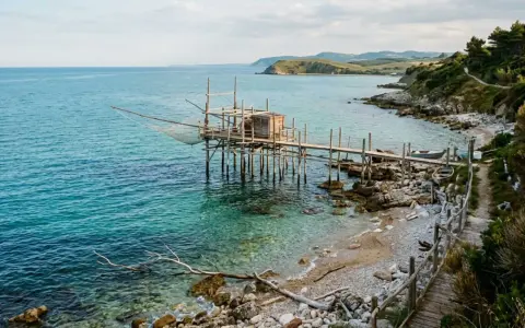Trabocco tradizionale sulle spiagge dell'Abruzzo, con il mare turchese e la costa rocciosa.