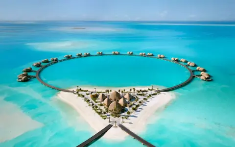 Resort circolare su un'isola tropicale, perfetto per le tue vacanze ad agosto. Case sull'acqua e sabbia bianca.