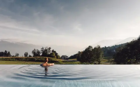 Donna rilassata in piscina a sfioro con vista sulle montagne, un'esperienza indimenticabile all'hotel Milla Montis.