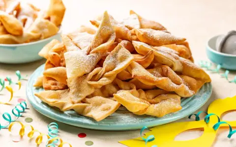 Dolci fritti a forma di fiocco, cosparsi di zucchero a velo, sono un classico di cosa si mangia a Carnevale in Italia.