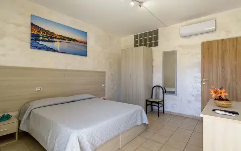 Camera accogliente all'Hotel Cristallo Paestum con letto matrimoniale, armadio, specchio e quadro con panorama marino.