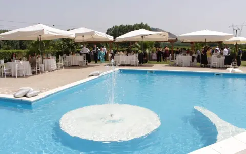 Un evento speciale alla Masseria Cardillo di Presenzano, con tavoli apparecchiati e ospiti vicino alla piscina con fontana.