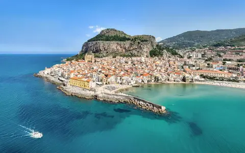Vista aerea di Cefalù, con le sue spiagge siciliane orientali, il borgo arroccato e il mare cristallino.