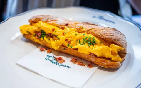 Panino con uova strapazzate, bacon croccante e erba cipollina. Un'ottima idea su cosa mangiare a Firenze per un pasto veloce e gustoso.