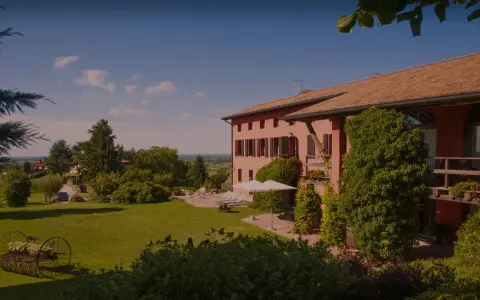 La casa rossa ai colli, immersa nel verde, offre un panorama incantevole. Un giardino curato con un antico attrezzo agricolo fiorito.