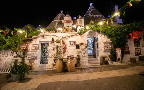 Trulli illuminati di notte ad Alberobello, con luci e decorazioni. Un invito a scoprire le cose da fare a Alberobello, tra negozi e prodotti tipici.