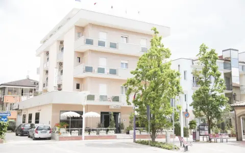 Hotel Atlantic Igea Marina: scopri i prezzi per la tua vacanza al mare. Edificio moderno con alberi verdi davanti.