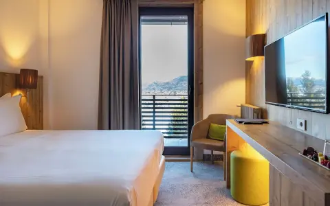 Camera accogliente con vista panoramica, tipica del Linta Hotel Asiago. Letto comodo, poltrona e balcone con paesaggio montano.