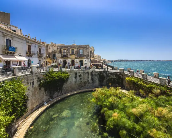 Passeggiata sul lungomare di Ortigia, Siracusa, ideale per un tour sicilia sud orientale 7 giorni. L'acqua cristallina e i papiri incantano.