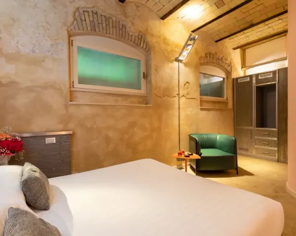 Camera accogliente con letto, poltrona verde e armadio. Un tocco di lusso, come un boscolo circo massimo, per un soggiorno indimenticabile.