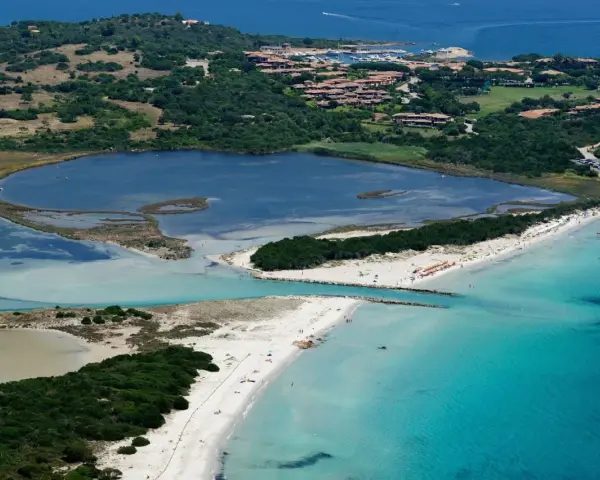 Vista aerea della spiaggia La Cinta con acque turchesi, lagune interne e vegetazione lussureggiante.