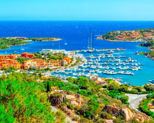 Vista panoramica di Porto Cervo con il suo porto turistico pieno di yacht e le case colorate che si affacciano sul mare cristallino. Un luogo da sogno per scoprire cosa vedere a Porto Cervo.
